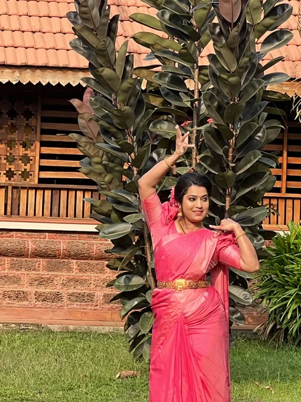 Dancer in a pink saree in a Kerala garden