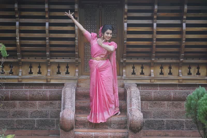 Dancer in a pink saree with arms raised