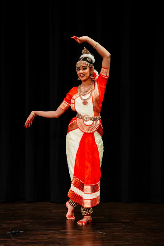Solo dancer in a classical pose on a dark stage