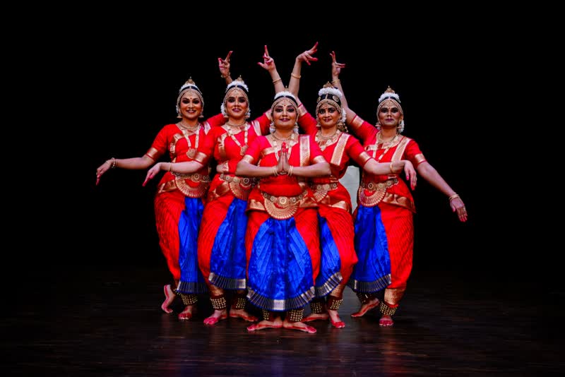 A group of dancers in red costumes in a stage formation