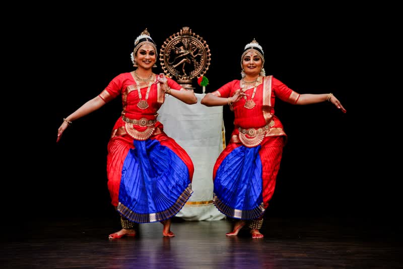 Bharatanatyam dancers in red and white costumes on stage