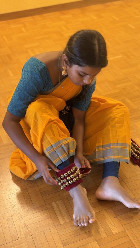 A student tying on her ankle bells (salangai)